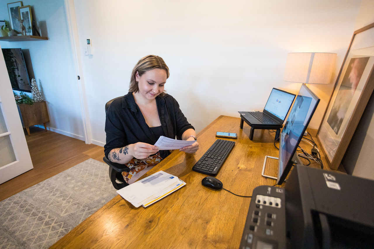 Woman looking at a Council bill or notice at a work desk in a home study.