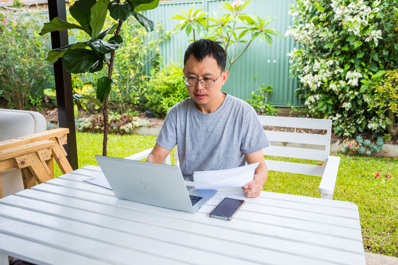 Person sitting at an outdoor table in front of a laptop paying a bill.