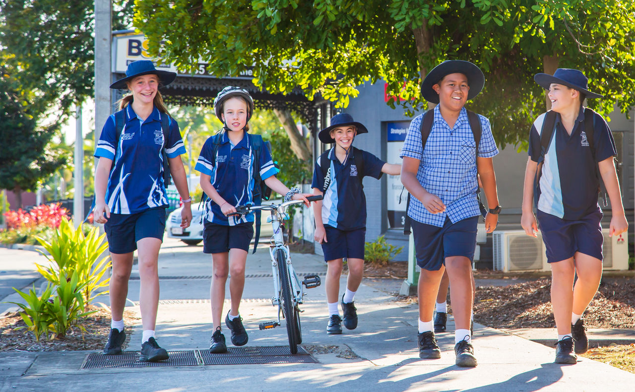 Boys and girls walking up the street wearing school uniform