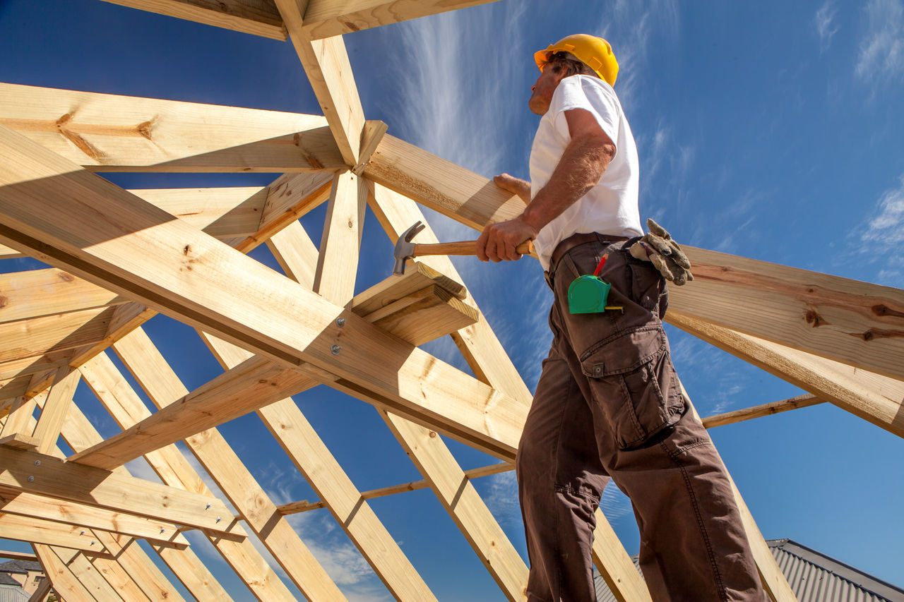 Builder working on a roof structure on a residential construction site.