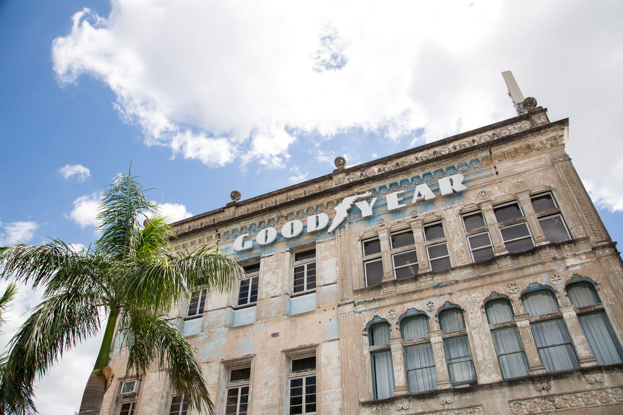 Facade of the former Taylor-Heaslop building at Woolloongabba featuring 'Good Year' signage above the top row of windows with a palm tree in the foreground.