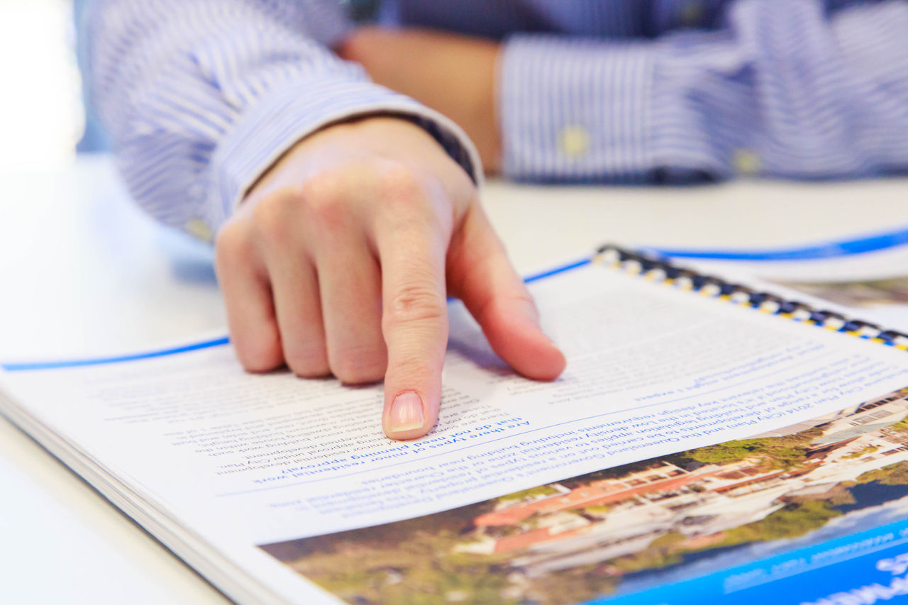 Close up of a man's hand pointing to a page on a planning document.