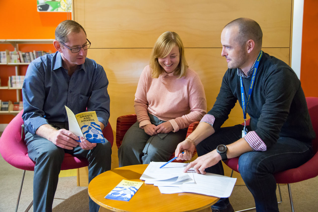 Three people meeting at a community grants information session.