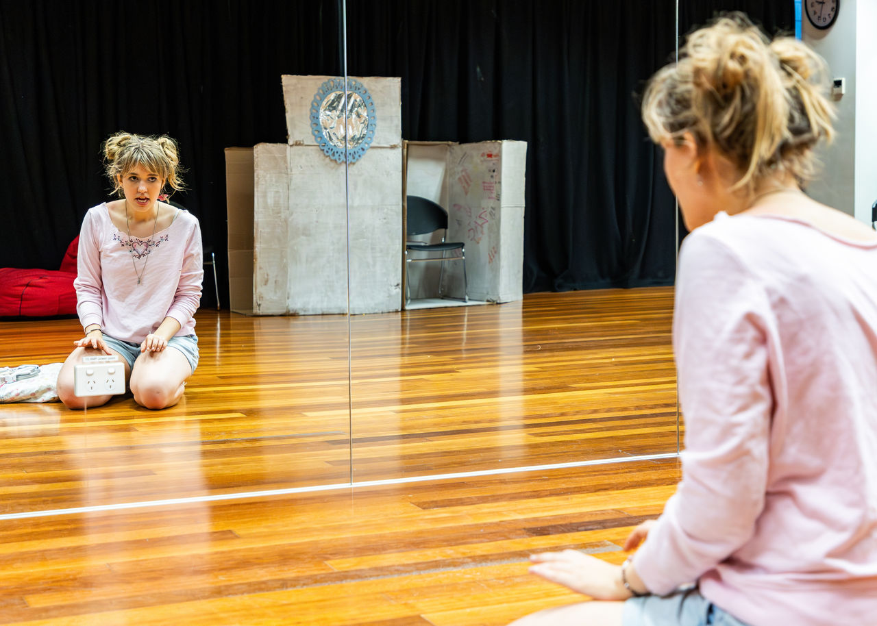 Young woman rehearsing a theatrical act in studio with mirrors at Visible Ink.