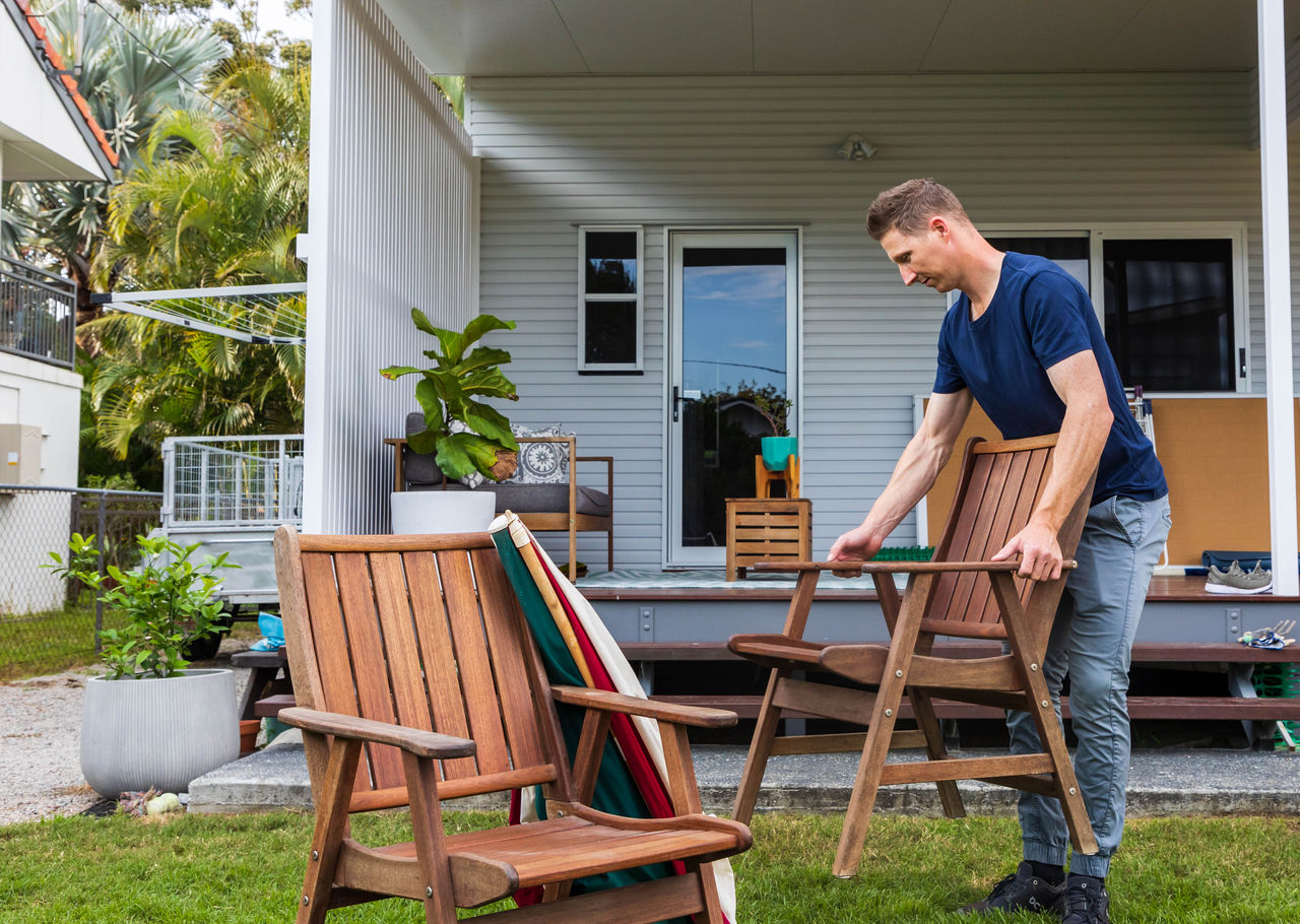 Person packing away wooden outdoor furniture.