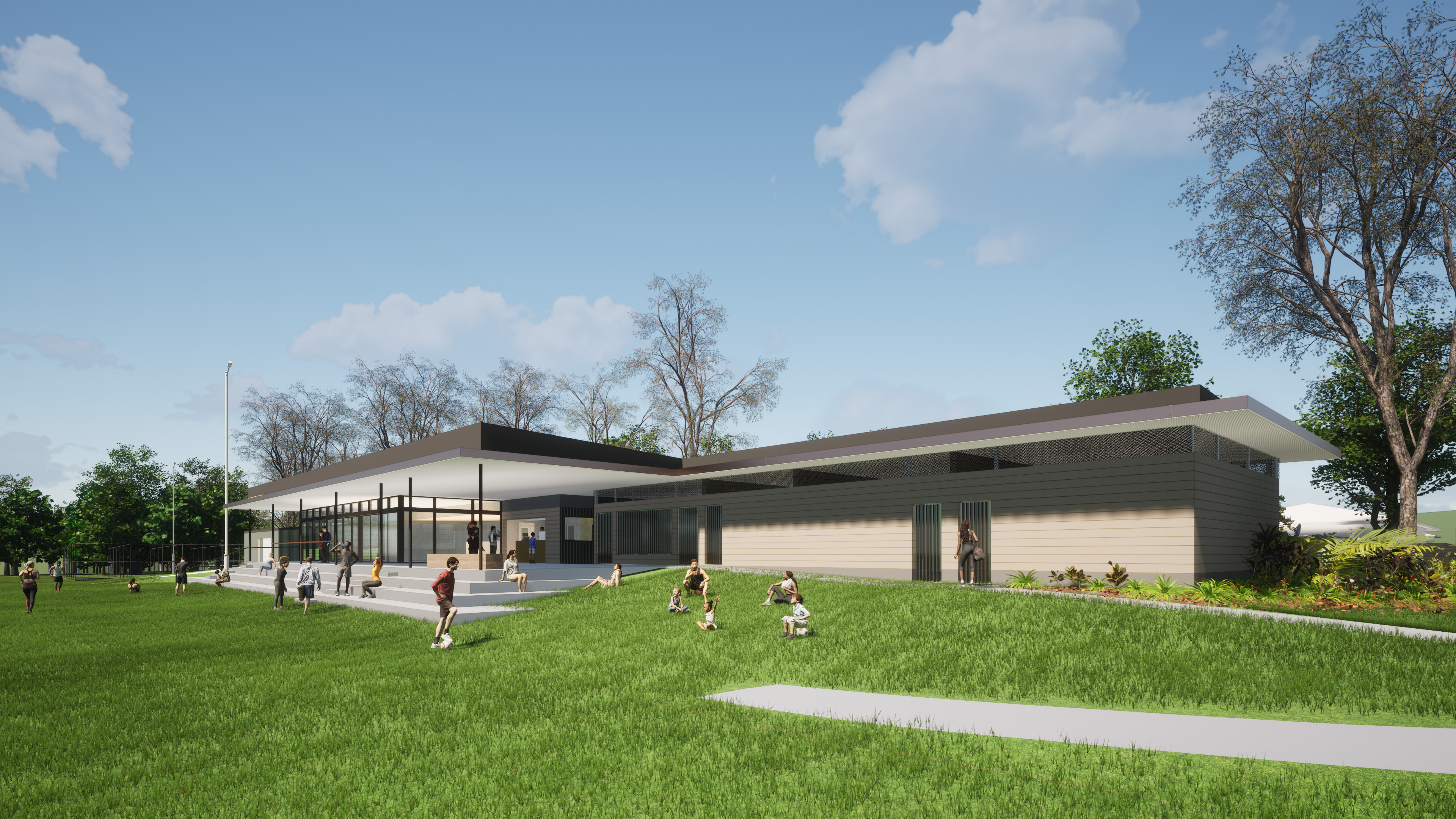 Image shows people playing on grass in front of new clubhouse. Clubhouse is central to the image. Changerooms are featured on the right of the building. The left of the building shows the function room with glass doors leading to an undercover viewing platform. Tiered concrete stairs connect the undercover viewing platform to the playing field.