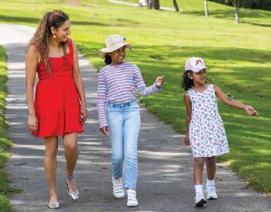 A woman and two children walking along a path through a green space