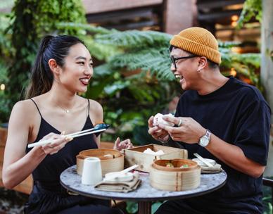 Man and woman seated at a table eating Asian food