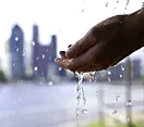 Hands catching droplets of water with city skyline in background